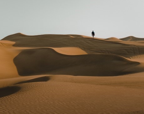 Silhouette of a person in the distance, walking in a desert. 